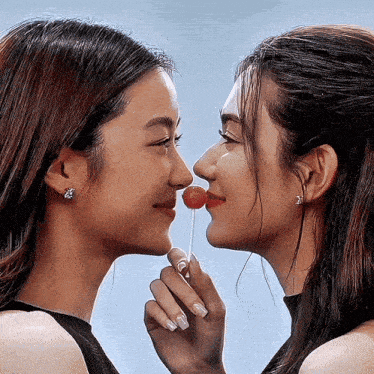 a woman is holding a lollipop to her nose