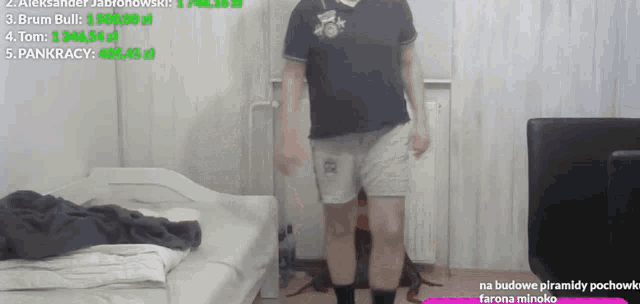 a man in a black shirt and grey shorts stands in a room