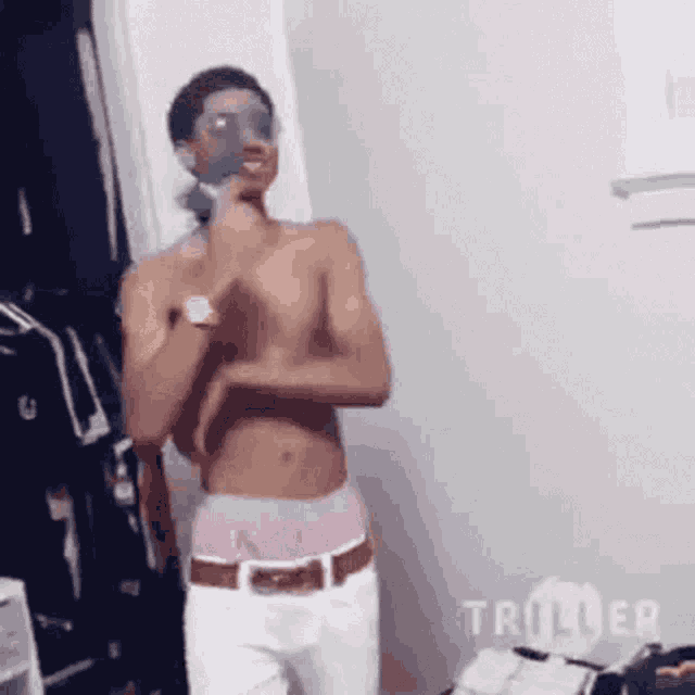 a shirtless man is wearing a mask on his face and standing in a room .