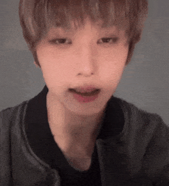a close up of a person 's face with their mouth open and a black jacket on .