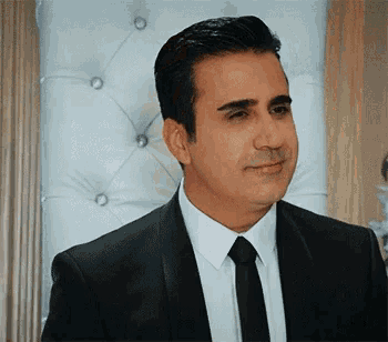 a man in a suit and tie is smiling and looking at the camera