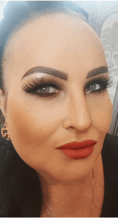 a close up of a woman 's face with long eyelashes and red lips