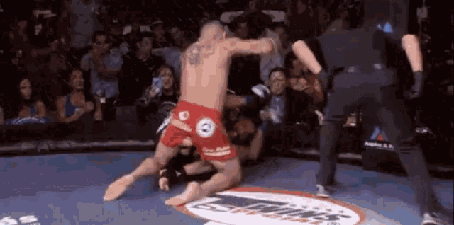 two men are fighting in a boxing ring with a referee in the background .