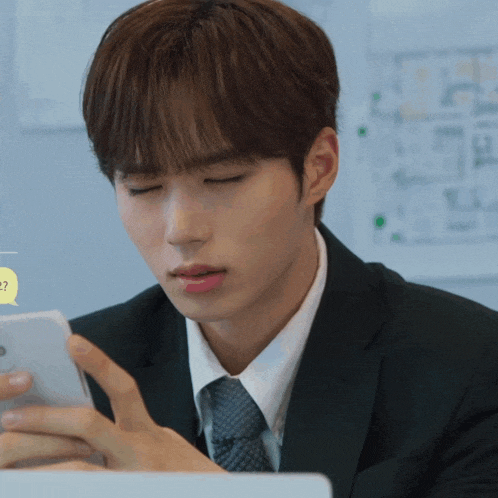 a man in a suit and tie is looking at his phone with a speech bubble that says ' ? ' on it
