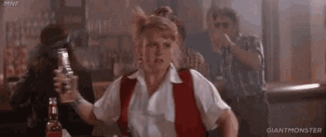 a woman in a white shirt and red tie is standing in a bar holding a glass .