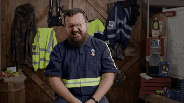 a man with a beard wearing a blue shirt with a pin that says ' donald trump ' on it