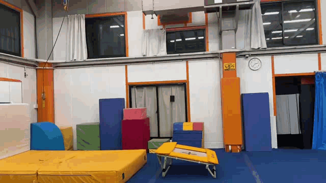 a gym with a clock on the wall and a sign that says ' emergency exit '