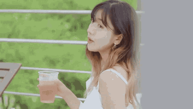 a close up of a woman holding a cup of water .