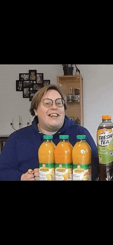 a man holding three bottles of fresh tea in front of him