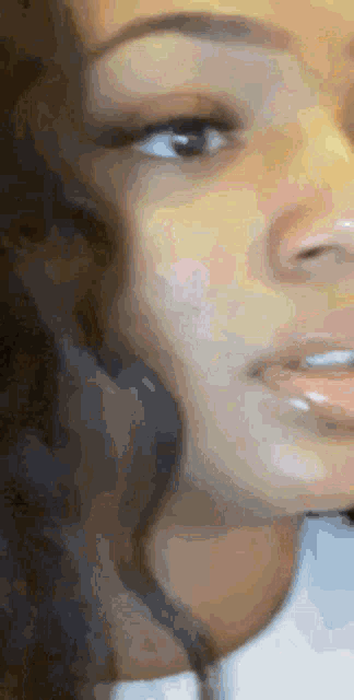 a close up of a woman 's face with curly hair and a white shirt .