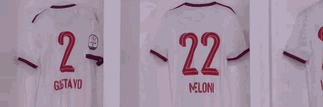 three white shirts with red numbers and meloni written on them