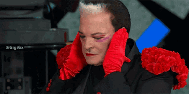 a man wearing red gloves and red flowers covering his face
