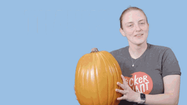 a woman in a sticker ant shirt holds a pumpkin in front of the words thanks pumpkin