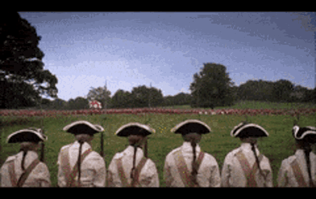 a group of soldiers are standing in a field with a flag in the background