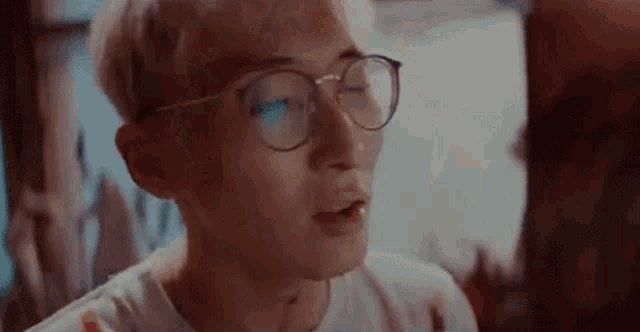 a young man wearing glasses and a white shirt is talking to someone .