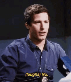 a man in a police uniform is laughing while talking to another man in a room .