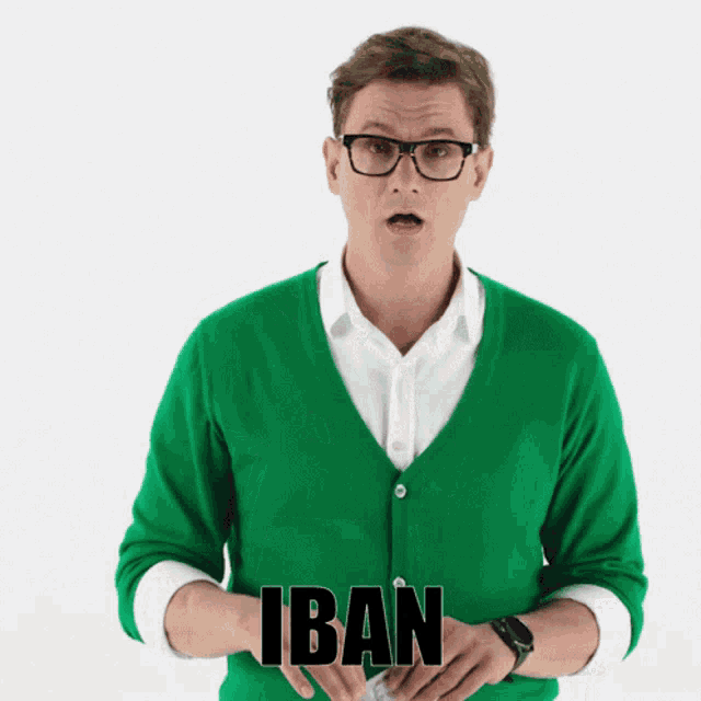 a man wearing glasses and a green cardigan has the word iban on his chest