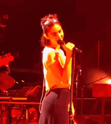 a woman is singing into a microphone on stage .