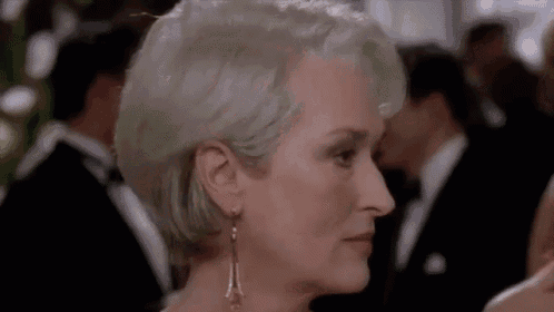 a close up of a woman 's face wearing earrings and a white dress .