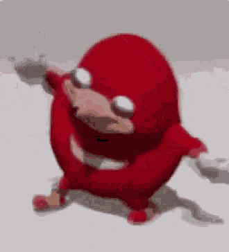 a red cartoon character is standing on a white surface and dancing .