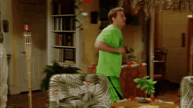 a man in a green shirt and green shorts is standing in a living room
