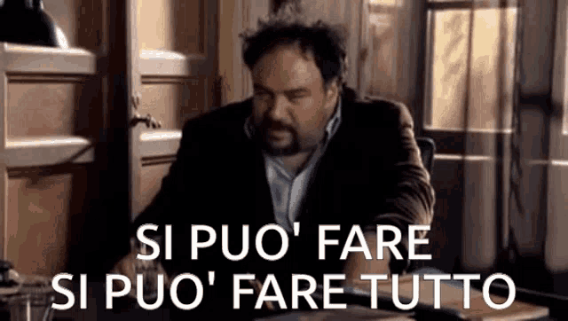 a man is sitting at a desk with the words si puo ' fare si puo ' fare tutto on the screen