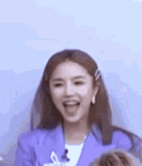 a woman in a purple suit is laughing and sticking her tongue out .