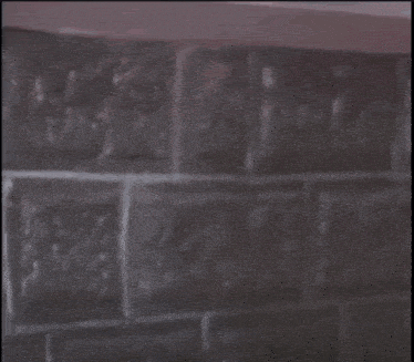 a man with a mustache is leaning against a brick wall .