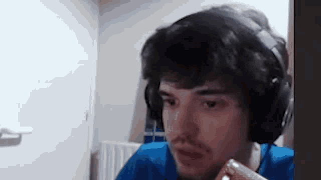 a man wearing headphones and a blue shirt is eating a piece of chocolate .