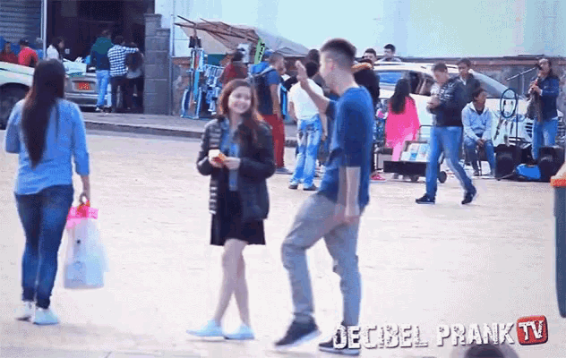 a group of people walking down a street with the words decibel prank tv on the bottom right