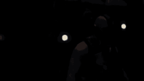 a man in a tank top is standing in front of a waterfall at night .