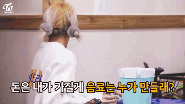 a woman is sitting at a table with a bucket in front of her and the word twice is on the back of her shirt