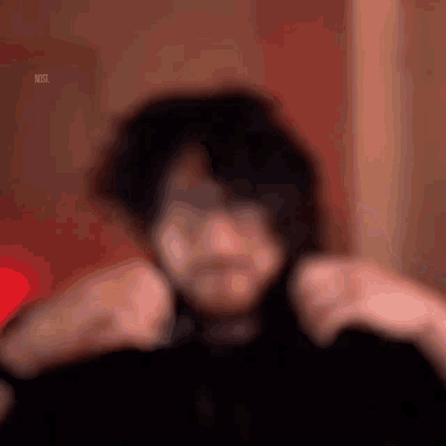 a blurry picture of a person 's face with their hands on their shoulders .