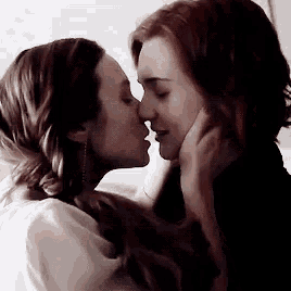 two women are kissing each other on the nose in a room .