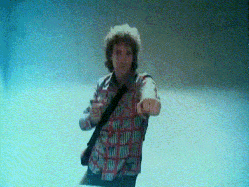 a man in a plaid shirt is pointing his finger at the camera