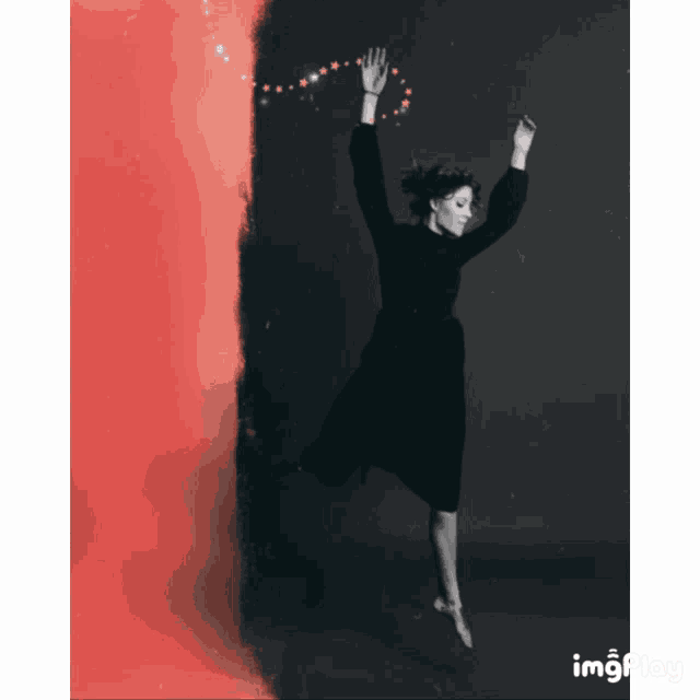 a woman in a black dress is jumping in the air with a red background