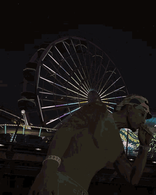 a shirtless man is standing in front of a ferris wheel at night