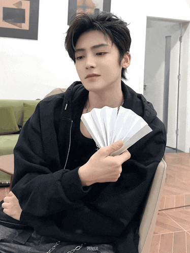 a man in a black jacket is holding a fan in his hand