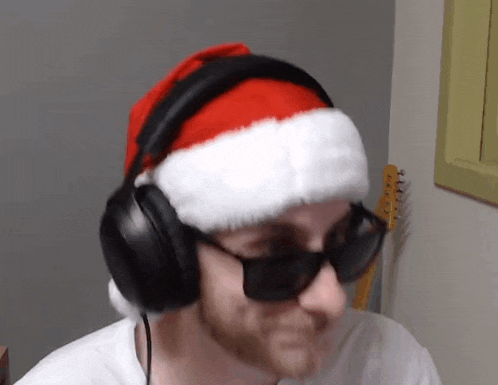 a man wearing a santa hat , headphones and sunglasses .