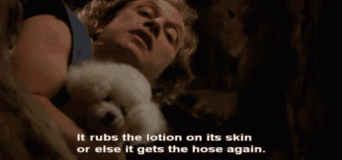 a man is holding a small white dog and says it rubs the lotion on its skin or else it gets the hose again .