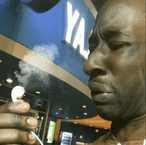 a man smoking an ear bud in front of a ya sign