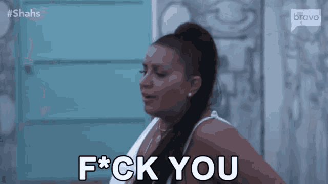 a woman is standing in front of a blue wall and saying `` f * ck you '' .