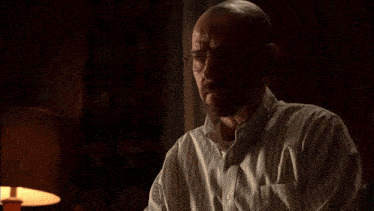 a man wearing glasses and a striped shirt is sitting in front of a lamp