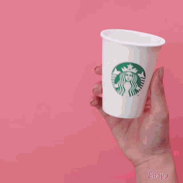 a person is holding a wooden spoon in front of a cup of chocolate