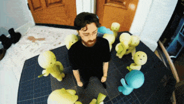 a man in a black shirt is surrounded by stuffed animals and a mat that says tnt on it