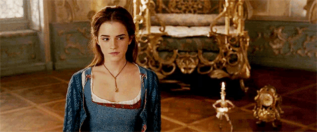 a woman in a blue dress is standing in a room next to a clock and a throne .