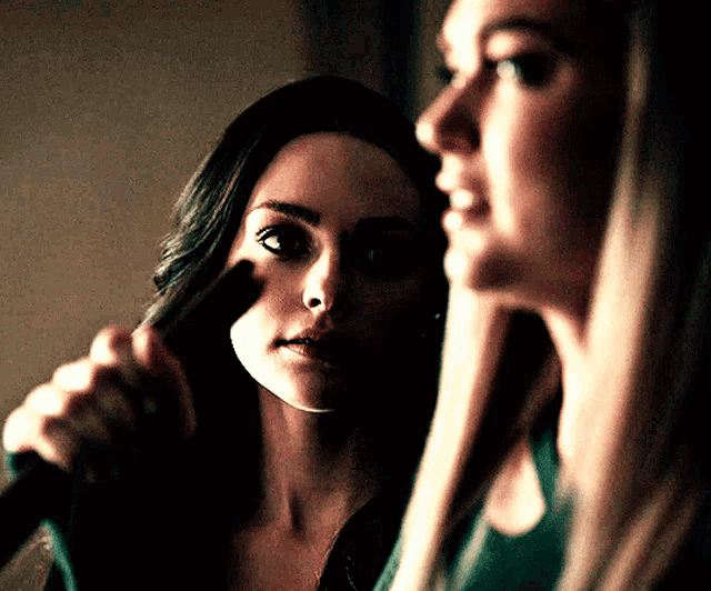 two women are standing next to each other and one is pointing at the other 's face