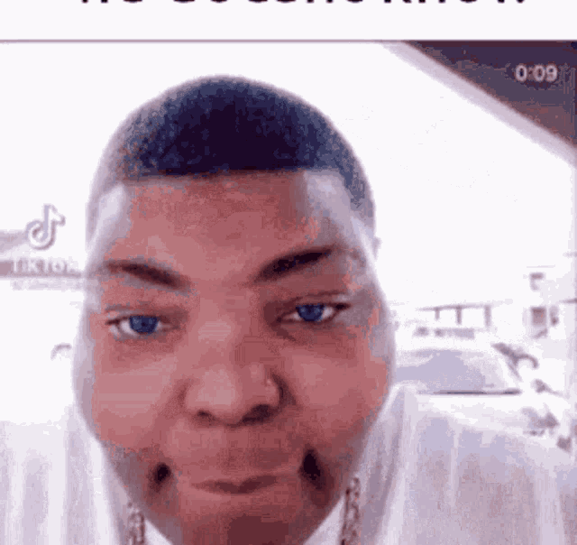 a man with blue eyes is making a funny face while wearing a white shirt .