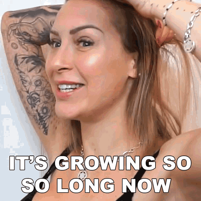 a woman with a tattoo on her arm is smiling with the words it 's growing so so long now