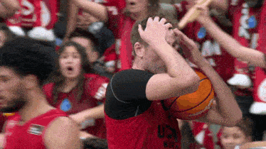 a man holding a basketball in front of a crowd wearing a jersey that says usc